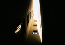 Photo looking up, skywards, between tall buildings on a narrow street in Girona, Catalonia